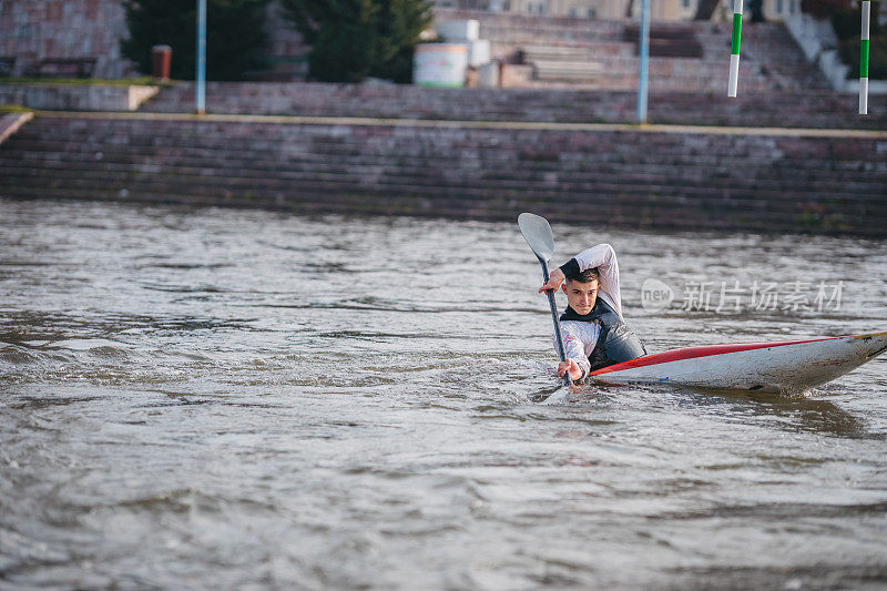 Young muscular man during kayak sprint training on still water